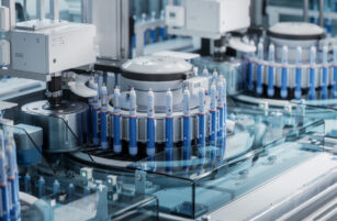 Close-up of automated laboratory equipment processing multiple test tubes filled with samples, set in a clean, modern medical or scientific facility with blue and metallic tones.